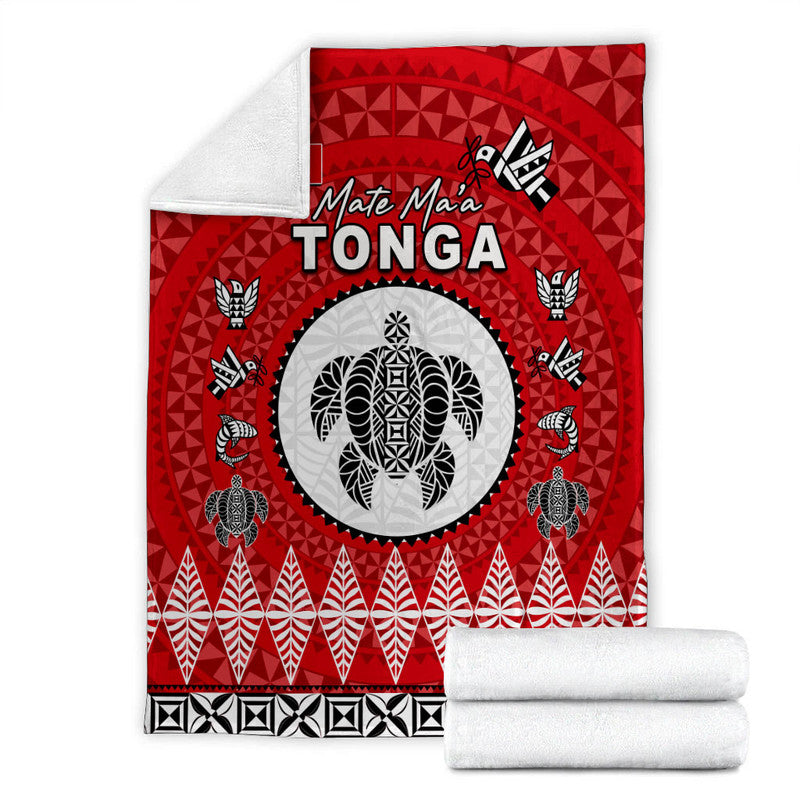 Red Tonga blanket with white rolled towels, “Mate Ma'a Tonga” text, and oval emblem