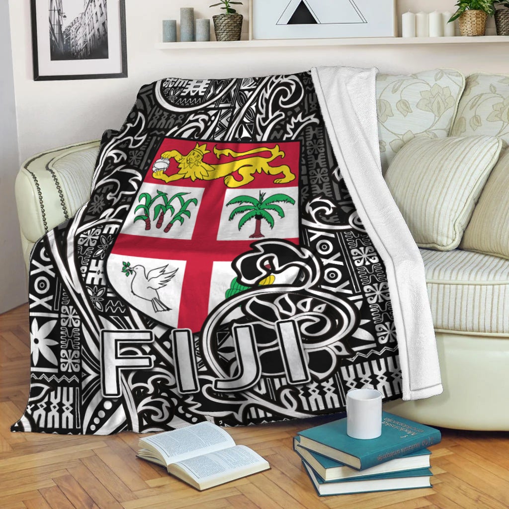 Black and white tapa-pattern blanket with Fiji flag center design, draped over sofa