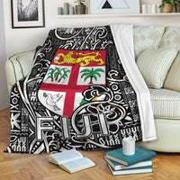 Black and white tapa-pattern blanket with Fiji flag center design, draped over sofa