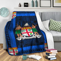 Blue and navy blanket on sofa with white throw; crest and dancer scene in center