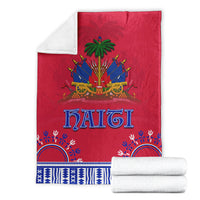 Folded red HAITI dashiki-style blanket with blue border and palm tree emblem; rolled pieces