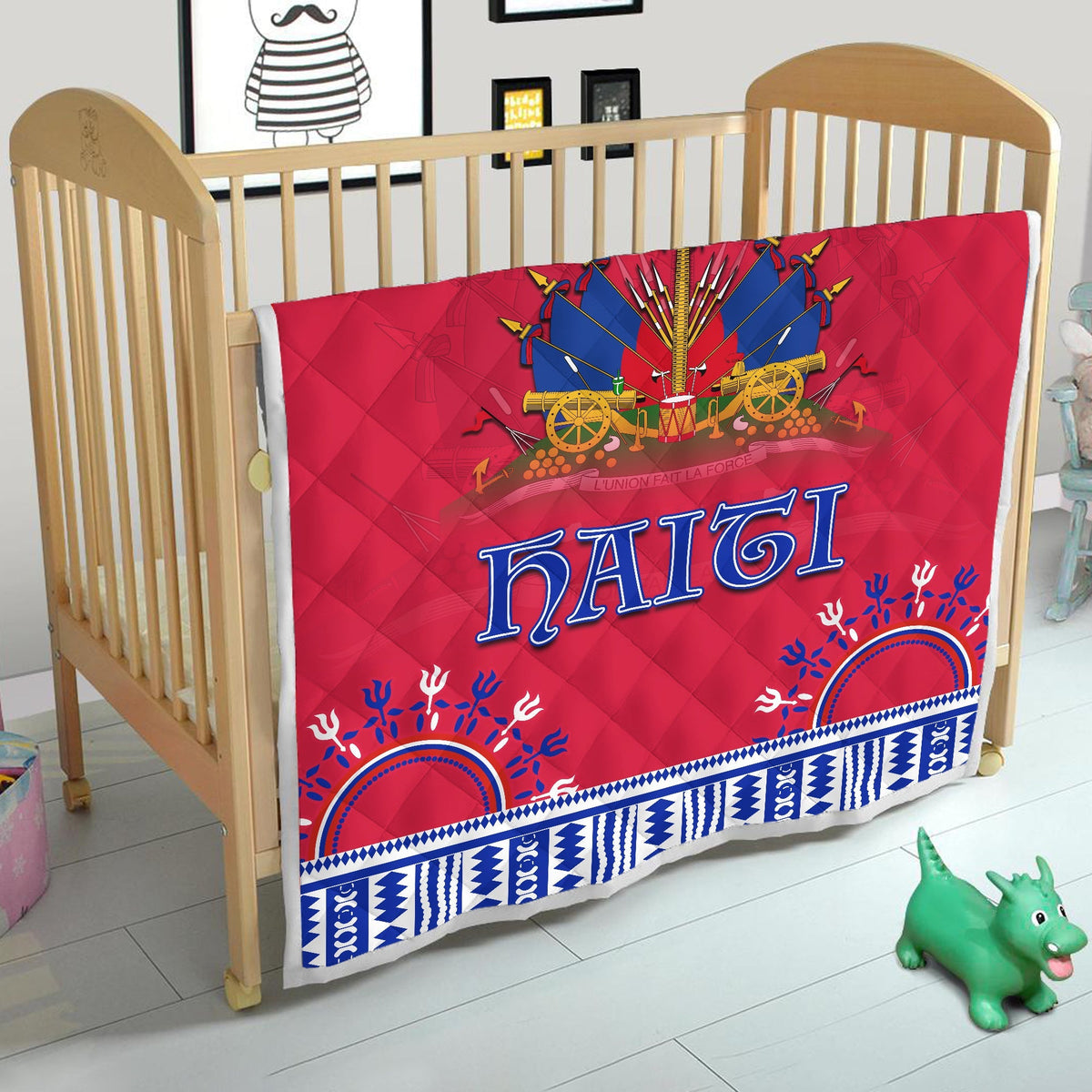 Red quilt with Haiti lettering and blue geometric trim, shown on baby bed