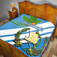 Guatemala quilt: blue design with quetzal, crest, and decorative plants on bed