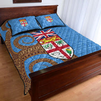 Blue Fiji Day quilt on bed with two pillows; circular motifs, shields, and “FIJI DAY” text