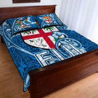 Blue quilt bed set with tapa motifs and central red-and-white cross crest panel