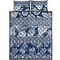 Flat lay of blue and white tropical leaves quilt bed set with two pillow shams and striped bands