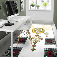 White rug with gold tree wreath and colorful square motifs across floor
