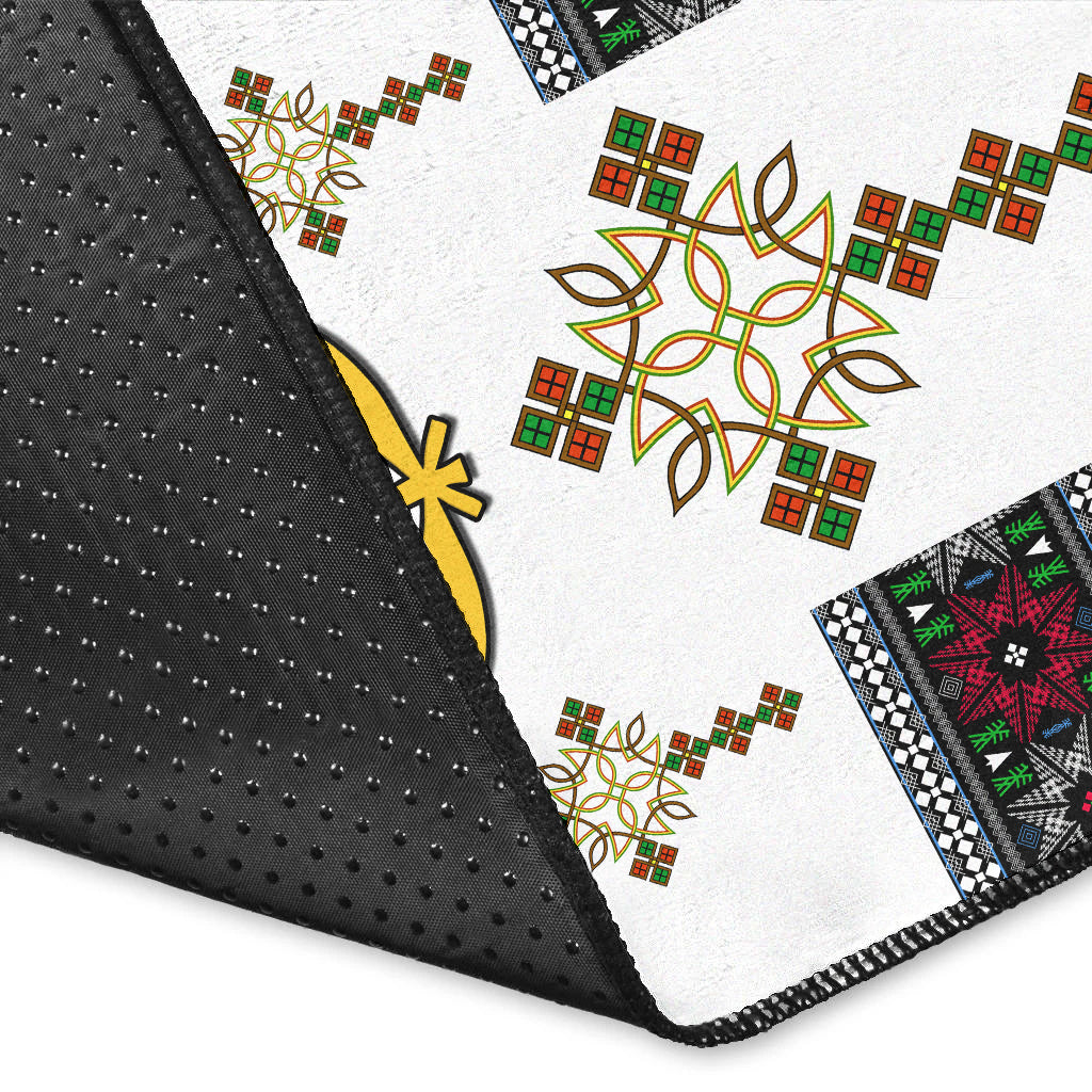 Close-up: white rug corner with black non-slip edge and gold/green/red motifs