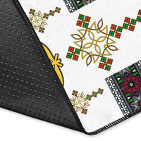 Close-up: white rug corner with black non-slip edge and gold/green/red motifs