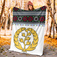 White outdoor blanket with gold tree emblem and red green black cross-pattern bands