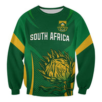 Green sweatshirt front with “SOUTH AFRICA”, crest, and yellow-green protea graphic