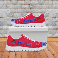 Red low-top sneakers with “Haiti” lettering, blue pattern accents, white sole, white laces