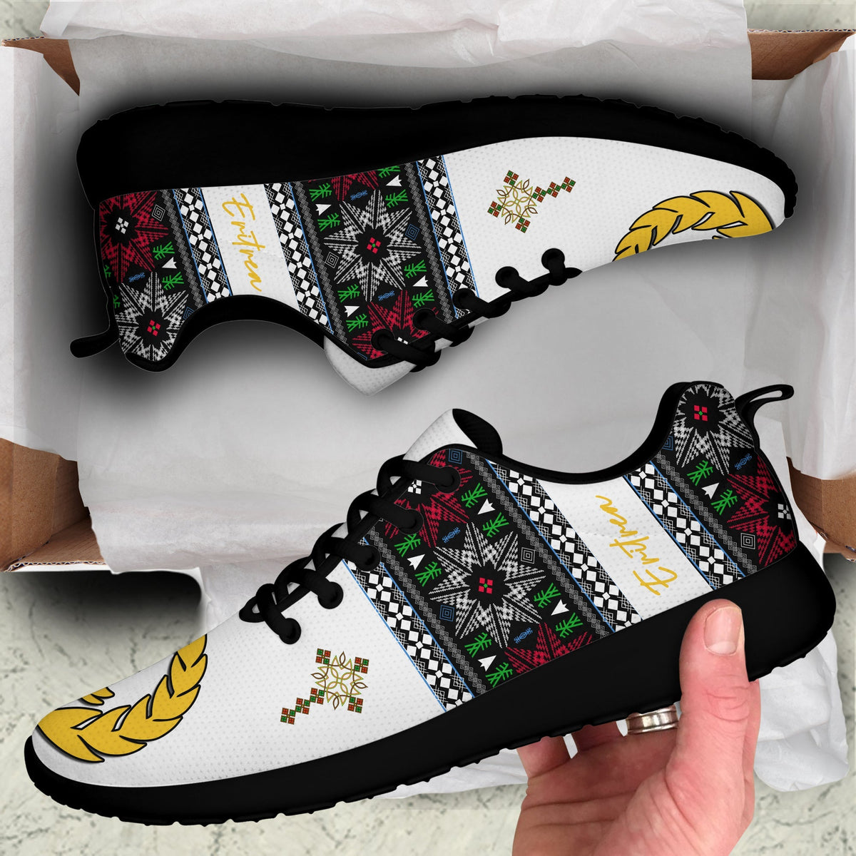 White sporty sneakers with black laces and multicolor Eritrea-pattern panel, wing logo