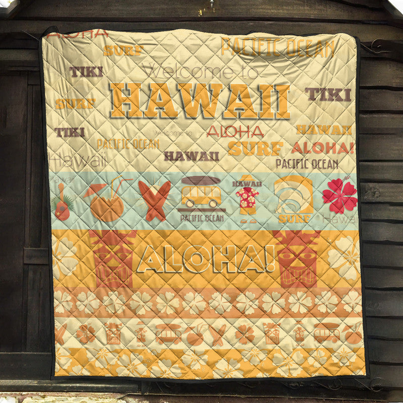 Quilt blanket with quilted diamond texture, yellow-beige base, surf and aloha graphics, black trim
