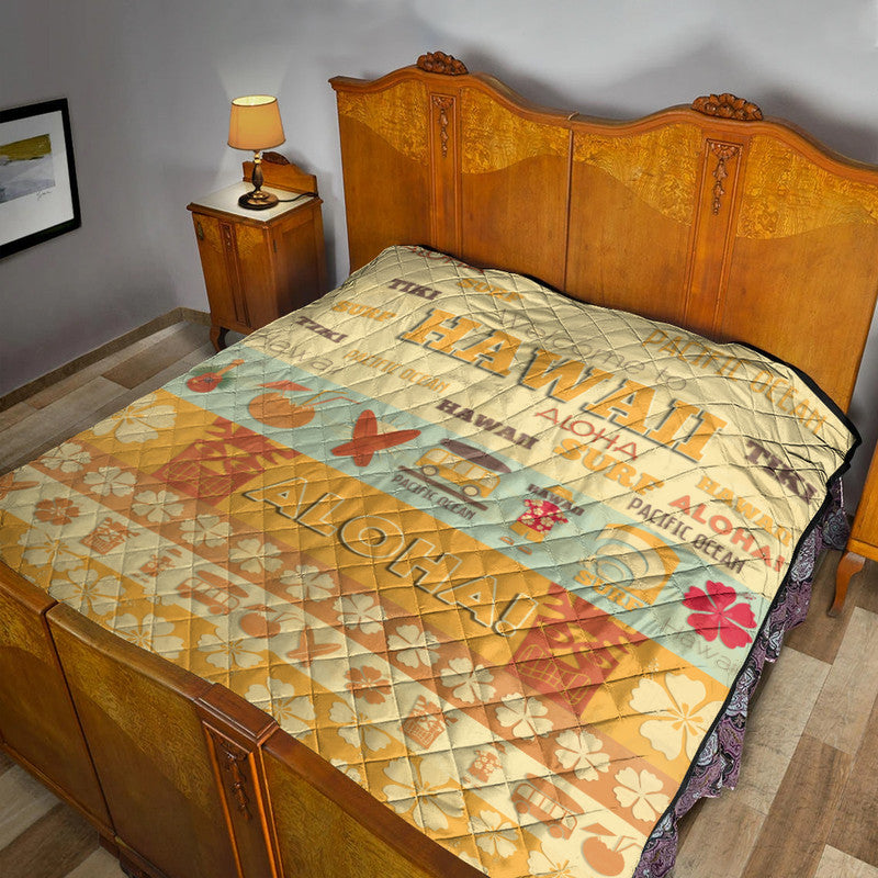 Quilt blanket with quilted diamond pattern, yellow-beige and teal surf print and flowers on bed