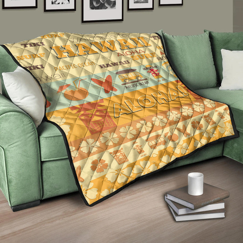 Quilt blanket with quilted diamond pattern, yellow-beige surf and floral graphics, on green sofa