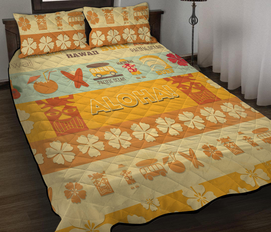 Quilt bed set with ALOHA lettering, hibiscus-style flowers, and two matching shams.