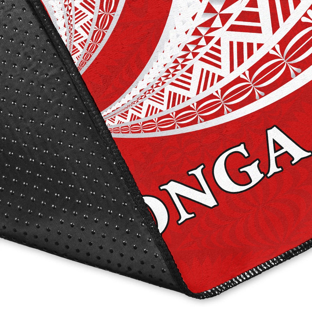 Close-up red Tonga rug corner: white tapa graphics, 'TONGA' text, black dotted backing
