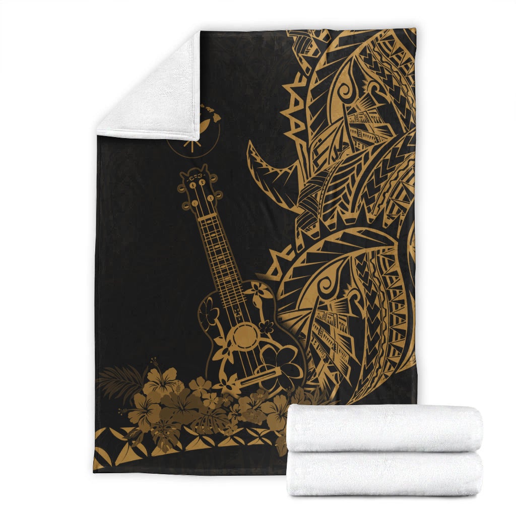 Black Polynesian blanket with gold ukulele and floral print, folded with rolled blankets