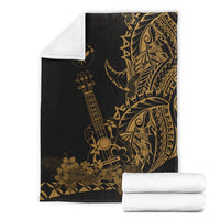 Black Polynesian blanket with gold ukulele and floral print, folded with rolled blankets