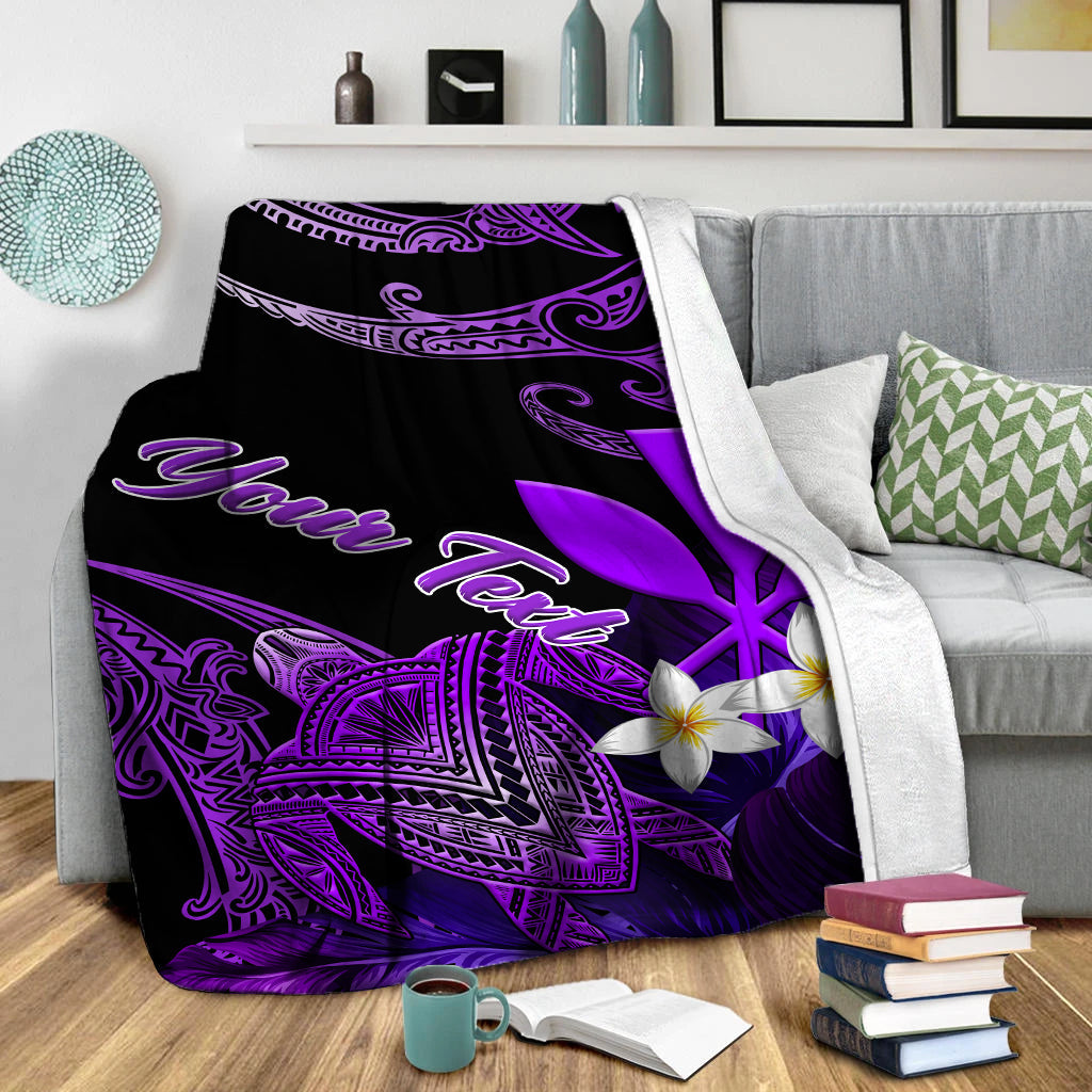 Black and purple turtle-and-plumeria blanket with Aloha script, folded on sofa