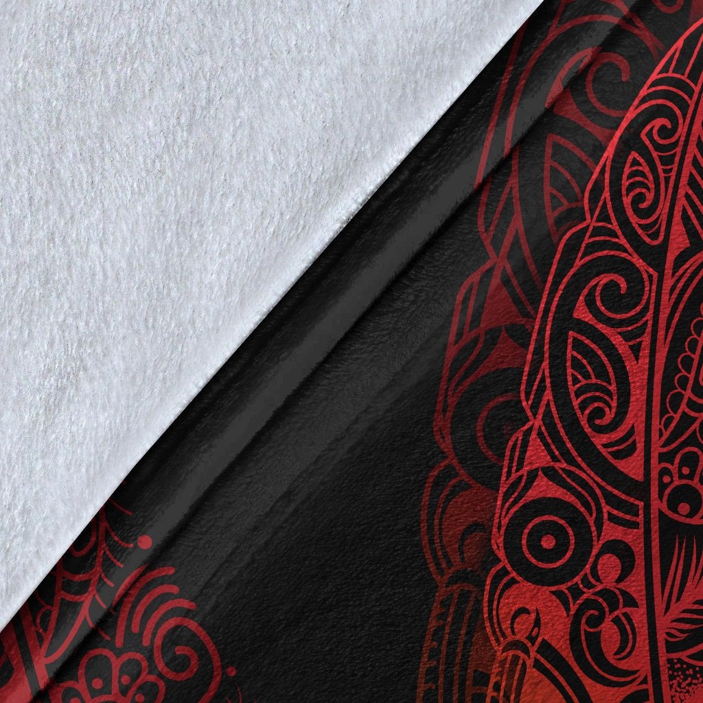 Close-up of black blanket fabric with red fern and manaia matau print detail