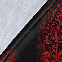 Close-up of black blanket fabric with red fern and manaia matau print detail