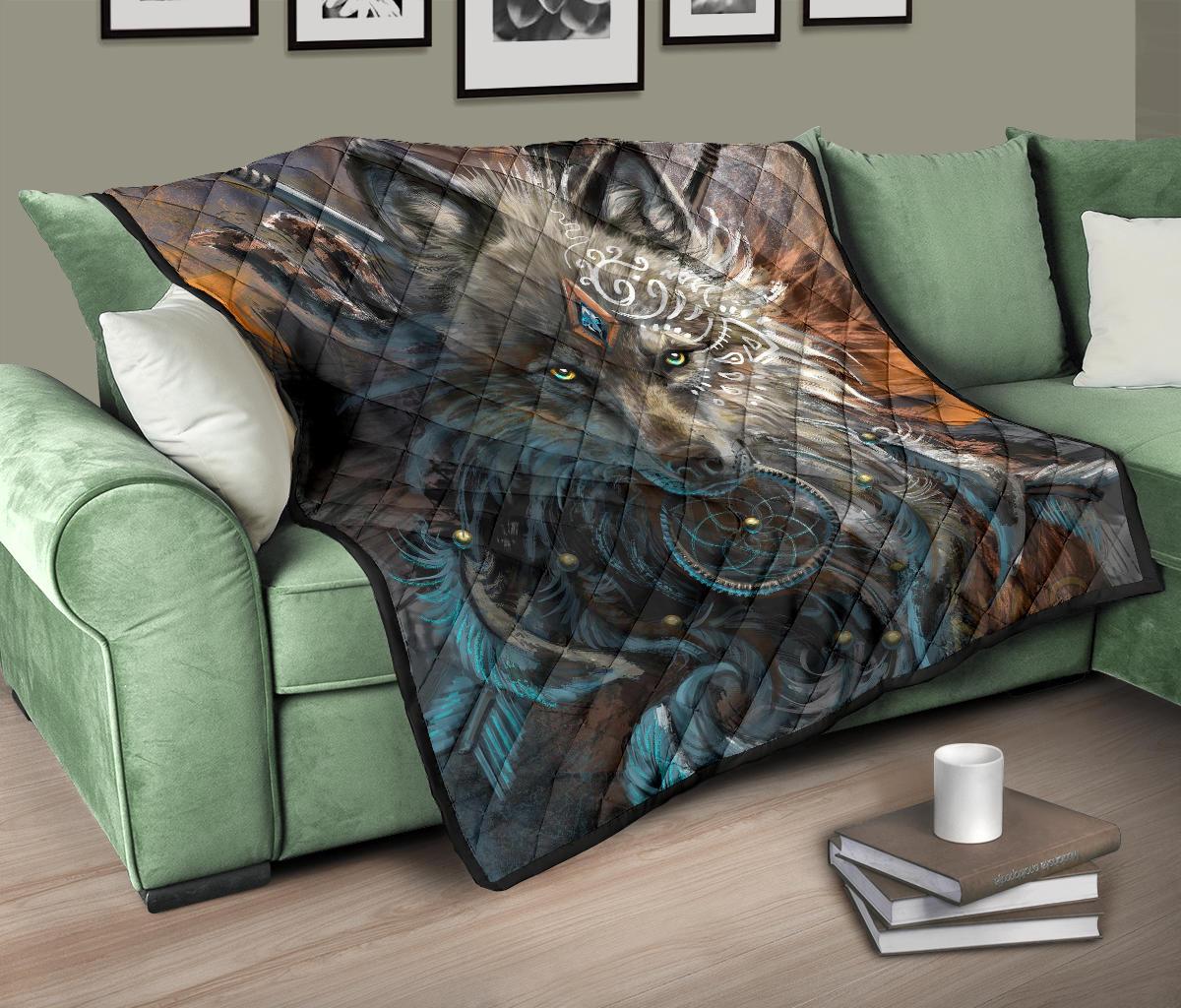 Quilt with multicolor wolf artwork on a green sofa, blue swirls and brown feather patterns