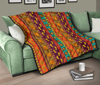 Multicolor patterned quilt laid across a couch arm, with repeating tribal graphic panels