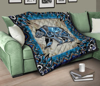 Quilt folded on sofa: blue geometric edge, stylized bear in blue and black, tan center