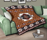 Brown quilt on green sofa with central emblem and red white black geometric stripe border