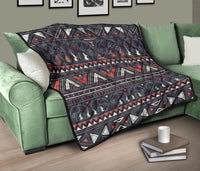 Native quilt on green couch: dark elephant row with red zigzags and beige triangle trim.