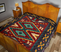 Native American-style quilt spread on bed, bold reds, teals, and yellows with border