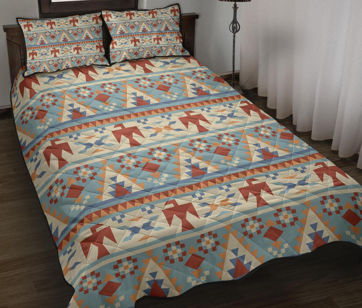 Light blue quilt bed set with red, tan, and navy geometric arrow pattern