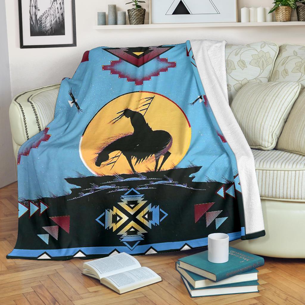 Light blue Native-style blanket draped over couch with black horse and yellow sun center