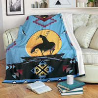 Light blue Native-style blanket draped over couch with black horse and yellow sun center