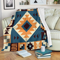 Navy arrow pattern blanket with orange, cream, and maroon geometric border, draped on sofa