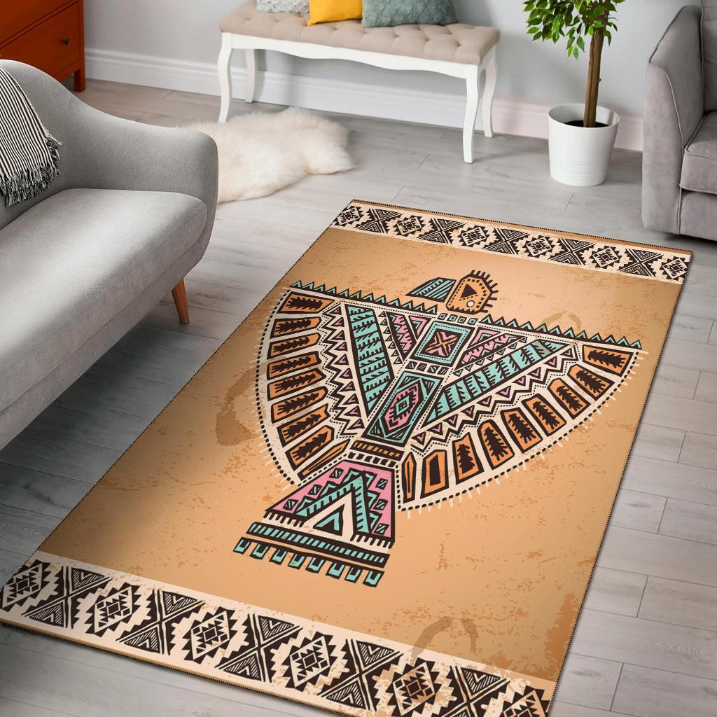 Beige area rug with native-style geometric bird and tribal patterns, black border trim