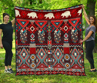 Native American-style quilt with white bear motifs and red geometric pattern border