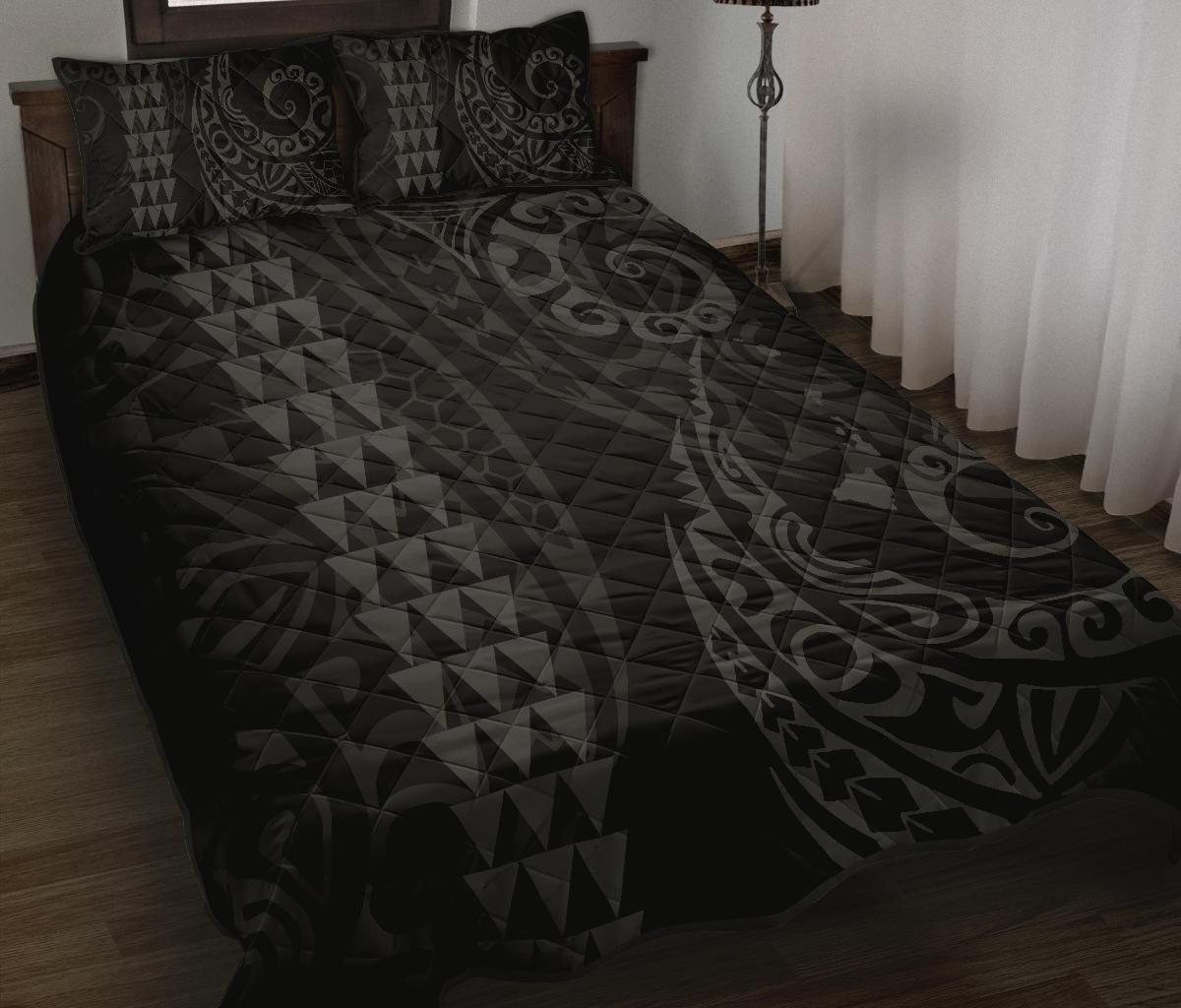 Grey patterned quilt cover on bed with two matching pillows, geometric triangles and swirls
