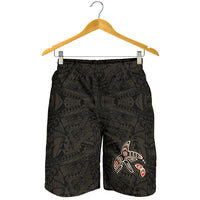 Black men’s shorts on hanger, all-over tribal print with killer whale patch graphic