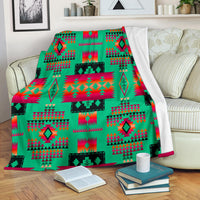 Light green tribe-style blanket with multicolor geometric pattern, folded on sofa