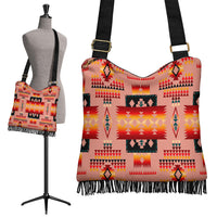 Tan crossbody bag with Native American pattern, black strap, gold buckle, fringe hem