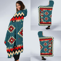 Teal hooded blanket with red-and-cream zigzag and diamond motifs, worn