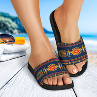 Multicolor patterned slide sandals on feet, black textured sole and blue strap