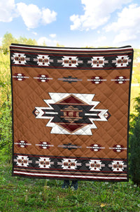 Brown quilt with central geometric star emblem, red white black accents, and patterned border