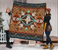 Brown quilt blanket with turquoise circular accents, feather centerpiece, and dark patterned border
