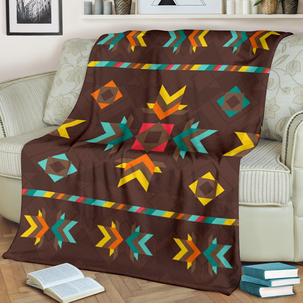 Brown blanket with multicolor geometric pattern, draped over a sofa arm