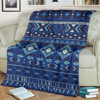 Geometric throw blanket with navy blue stripes and diamond shapes on armchair