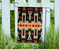 Multicolor native-style geometric flag on two metal stakes, black background with cross motifs